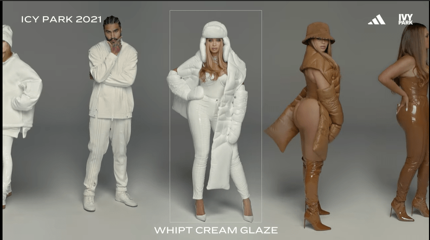 Beyoncé dressed in a white ensemble with a white furry hat and long white coat. she stands next to herself in a brown bodysuit and scarf (on the right) and next to a black man wearing a white sweats outfit.